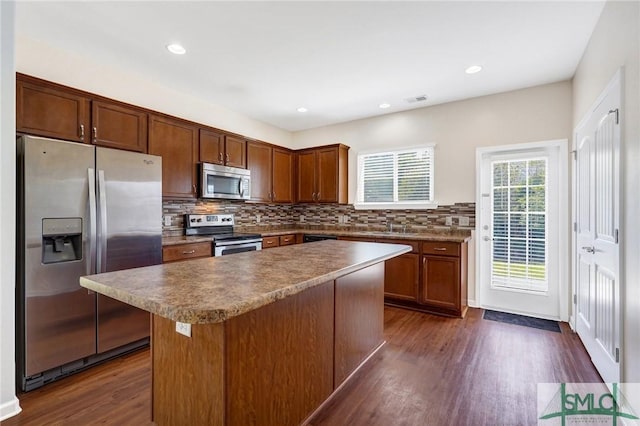 kitchen with a center island, stainless steel appliances, tasteful backsplash, visible vents, and dark wood-type flooring