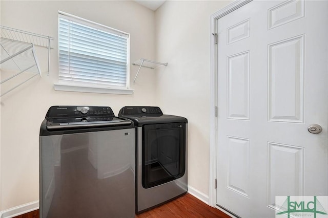 clothes washing area with laundry area, washer and clothes dryer, baseboards, and dark wood-type flooring