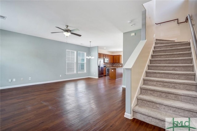 stairway with baseboards, ceiling fan with notable chandelier, wood finished floors, and visible vents
