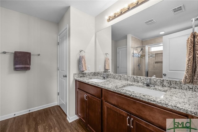 full bath featuring a sink, visible vents, wood finished floors, and a shower stall