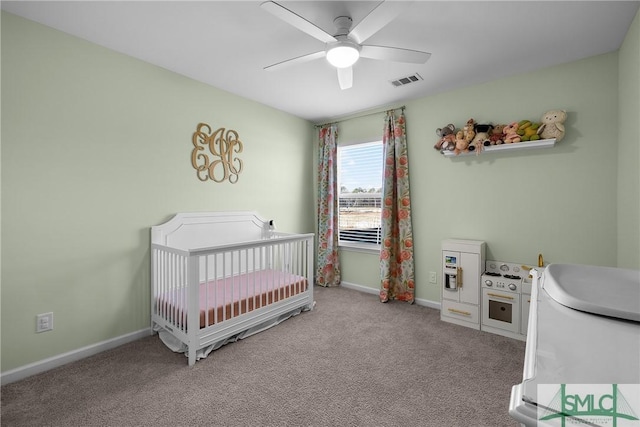 carpeted bedroom with a nursery area, baseboards, visible vents, and ceiling fan