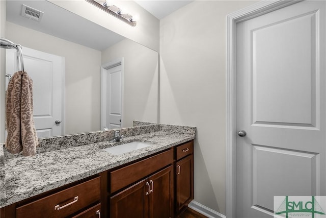 bathroom featuring visible vents, baseboards, and vanity