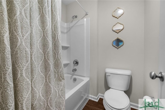 bathroom with baseboards, toilet, wood finished floors, and shower / tub combo