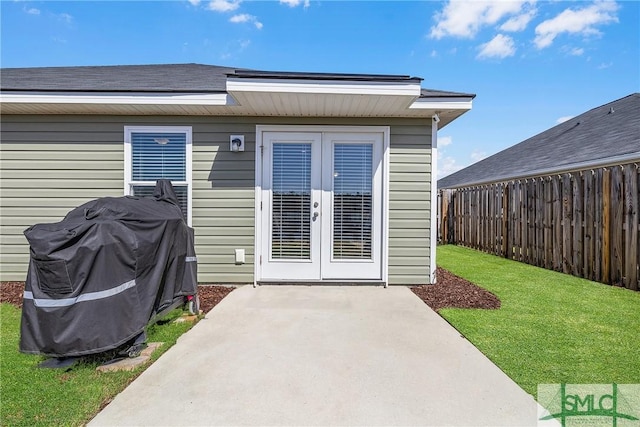 doorway to property featuring a patio, fence, french doors, and a lawn