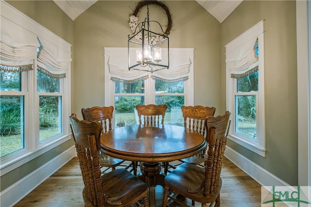 dining room with wood finished floors, baseboards, lofted ceiling, and a chandelier