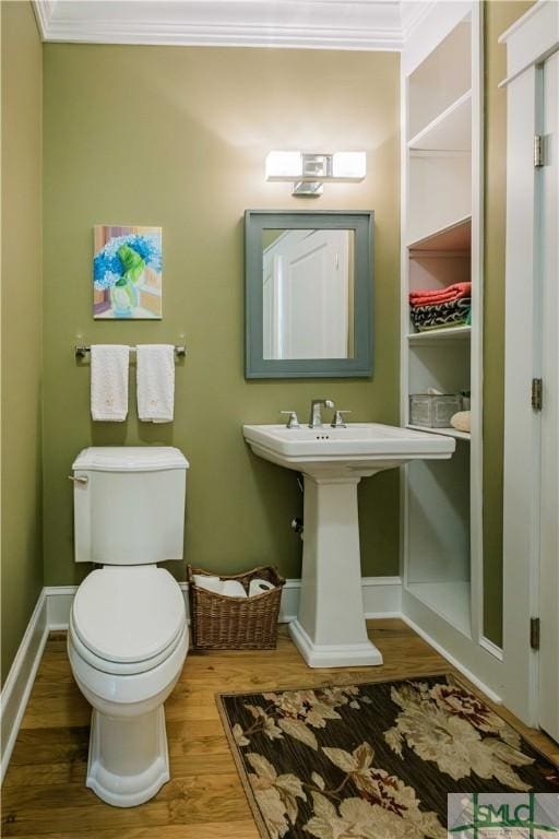 bathroom with toilet, crown molding, baseboards, and wood finished floors