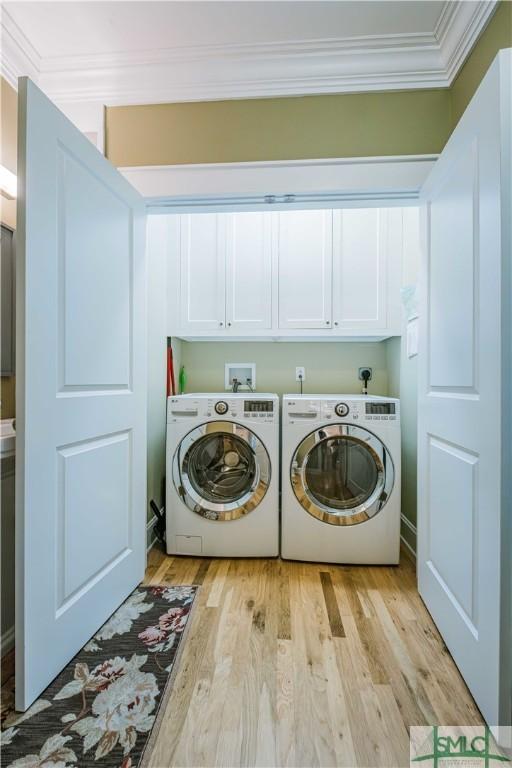 laundry area featuring washer and dryer, cabinet space, light wood-type flooring, and ornamental molding