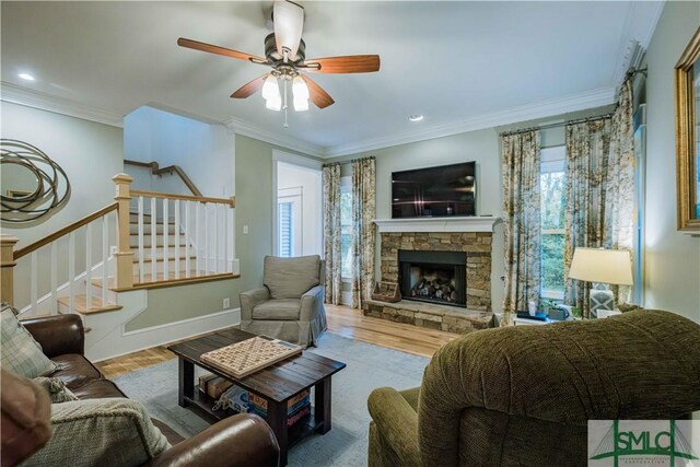 living area with wood finished floors, a fireplace, ornamental molding, stairs, and ceiling fan