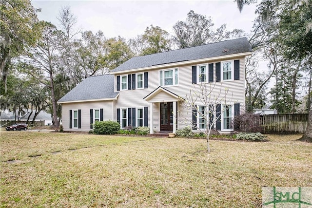 colonial home featuring a front lawn and fence