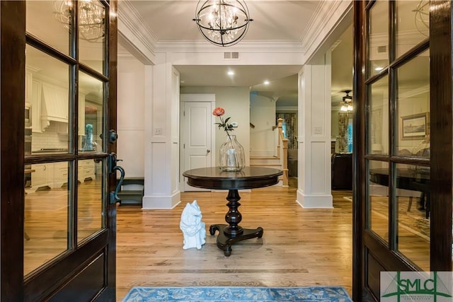 entryway featuring a decorative wall, light wood-style floors, visible vents, and ornamental molding