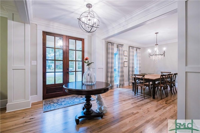 dining area with light wood-style flooring, a notable chandelier, french doors, and ornamental molding