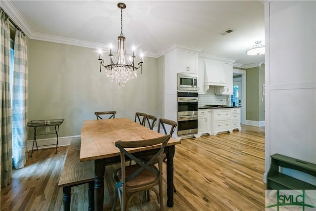 dining space with light wood finished floors, visible vents, and crown molding