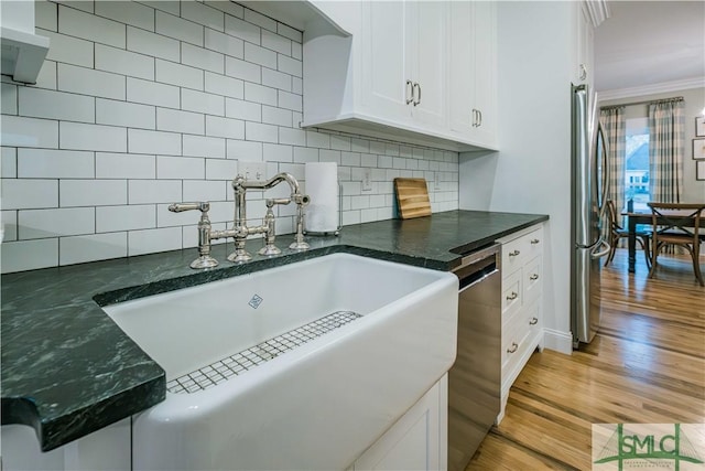 kitchen featuring a sink, stainless steel appliances, light wood-style floors, crown molding, and backsplash