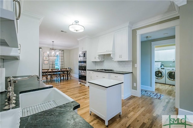 kitchen featuring dark countertops, visible vents, washing machine and dryer, stainless steel appliances, and white cabinetry