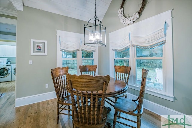 dining space with wood finished floors, baseboards, lofted ceiling, separate washer and dryer, and a chandelier