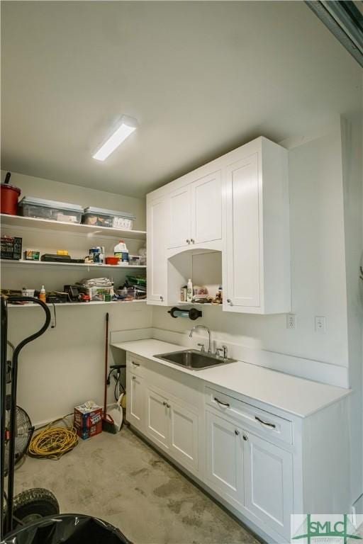 interior space with a sink, open shelves, light countertops, and white cabinetry