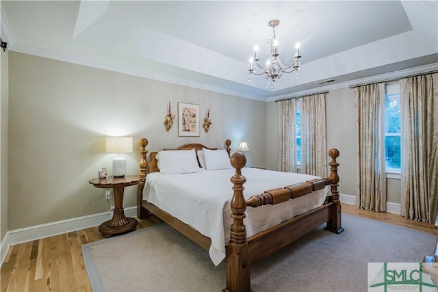 bedroom featuring visible vents, a raised ceiling, baseboards, and wood finished floors