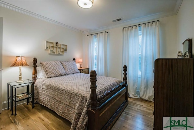 bedroom with visible vents, wood finished floors, and ornamental molding