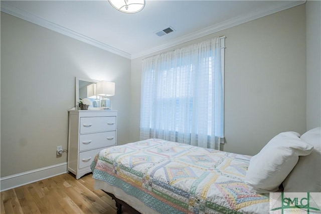 bedroom with baseboards, wood finished floors, visible vents, and ornamental molding