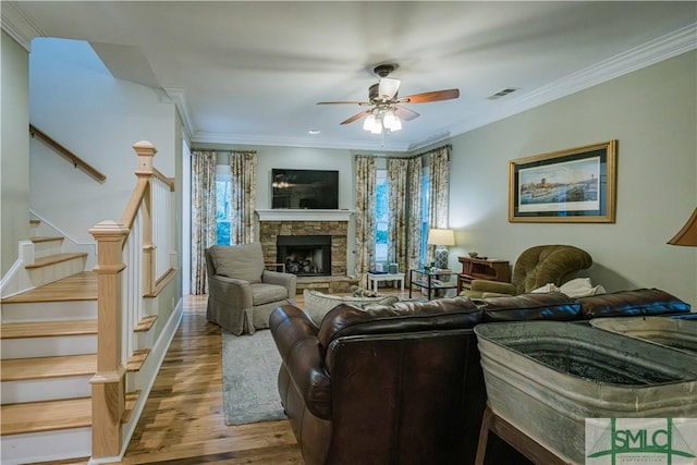 living area with a wealth of natural light, visible vents, wood finished floors, and crown molding