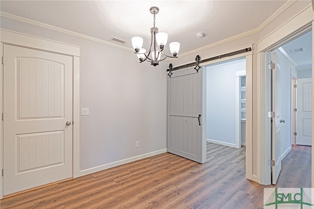 unfurnished dining area with visible vents, crown molding, baseboards, a barn door, and wood finished floors