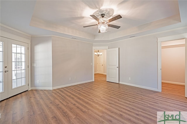 empty room with french doors, a raised ceiling, and wood finished floors