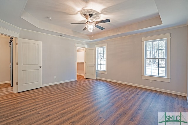 unfurnished bedroom featuring baseboards, a raised ceiling, and dark wood finished floors