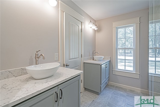 bathroom featuring two vanities, baseboards, and a sink