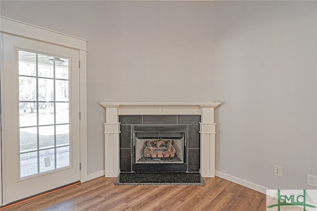 room details with wood finished floors, baseboards, and a tile fireplace