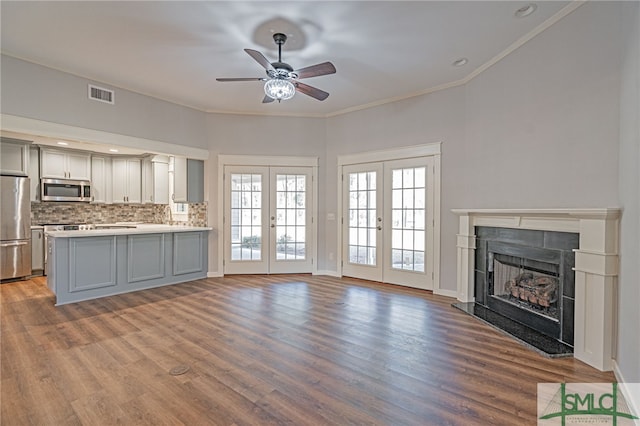 unfurnished living room with a high end fireplace, visible vents, crown molding, french doors, and wood finished floors