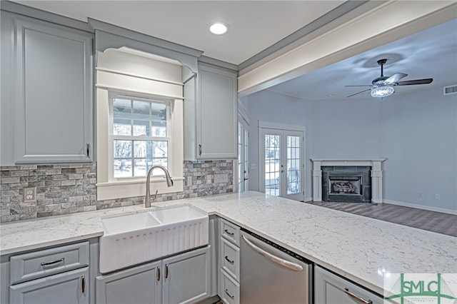 kitchen featuring a sink, dishwasher, a fireplace, and gray cabinetry