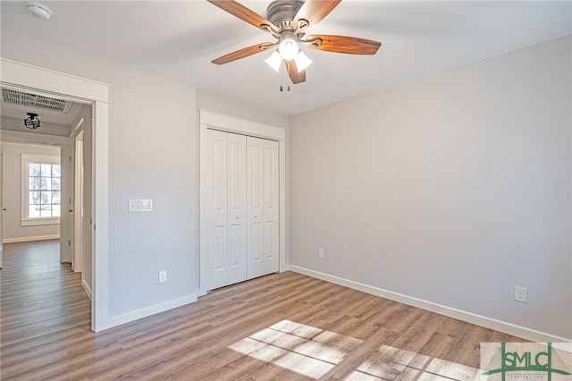 unfurnished bedroom featuring light wood-type flooring, visible vents, a closet, baseboards, and ceiling fan