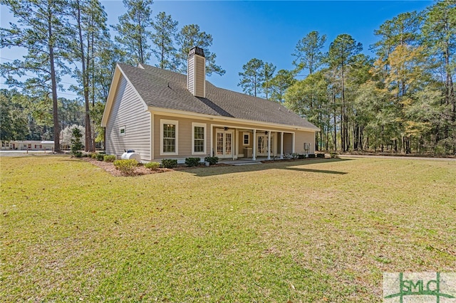 rear view of property featuring roof with shingles, a lawn, french doors, a chimney, and a ceiling fan