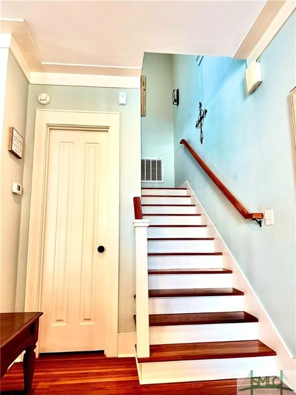 stairs with wood finished floors and visible vents