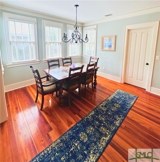 dining area with baseboards, visible vents, an inviting chandelier, and wood finished floors