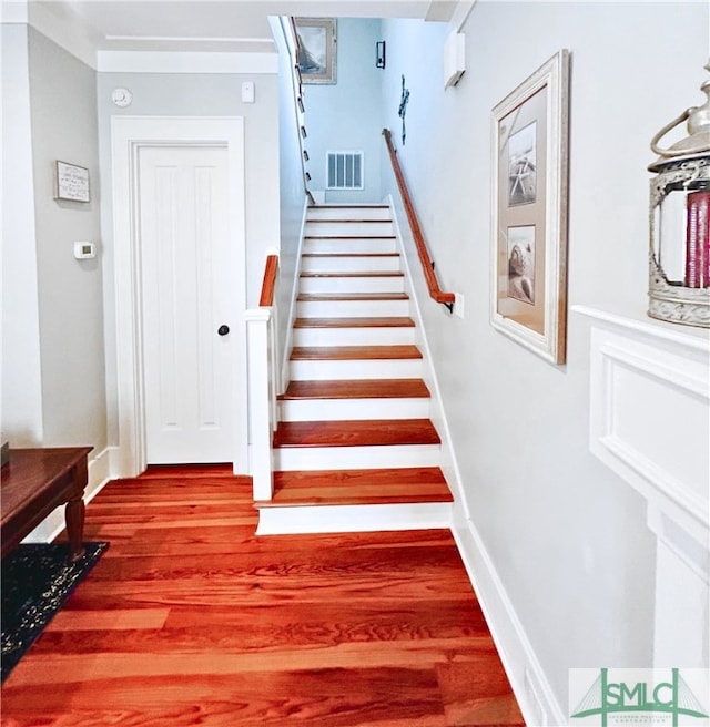 stairway featuring wood finished floors, baseboards, and visible vents