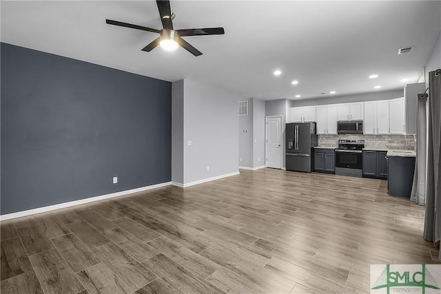 kitchen with tasteful backsplash, ceiling fan, light countertops, appliances with stainless steel finishes, and wood finished floors