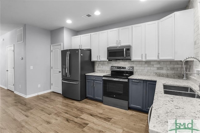 kitchen with light wood finished floors, visible vents, backsplash, and appliances with stainless steel finishes