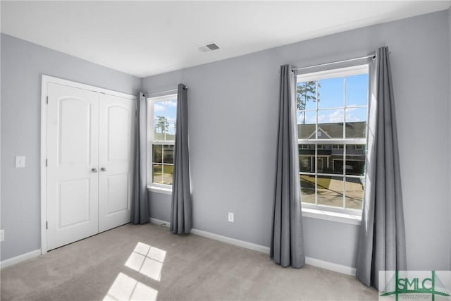 unfurnished bedroom with a closet, light carpet, baseboards, and visible vents