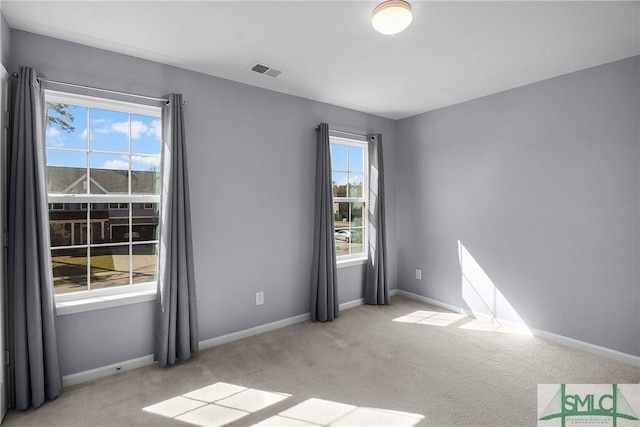 unfurnished room featuring visible vents, baseboards, and light colored carpet