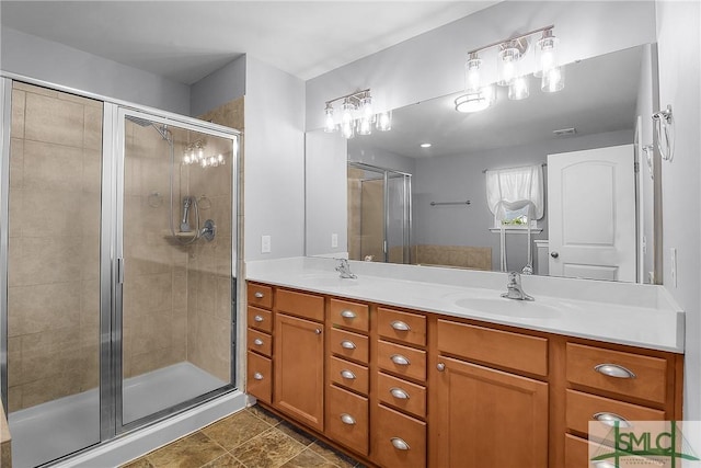 bathroom featuring double vanity, a stall shower, and a sink