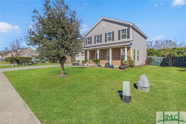 traditional-style home featuring a front yard, fence, driveway, a garage, and brick siding