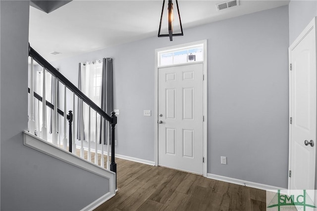 entrance foyer featuring visible vents, baseboards, wood finished floors, and stairway