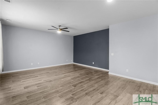 unfurnished room featuring visible vents, wood finished floors, baseboards, and ceiling fan