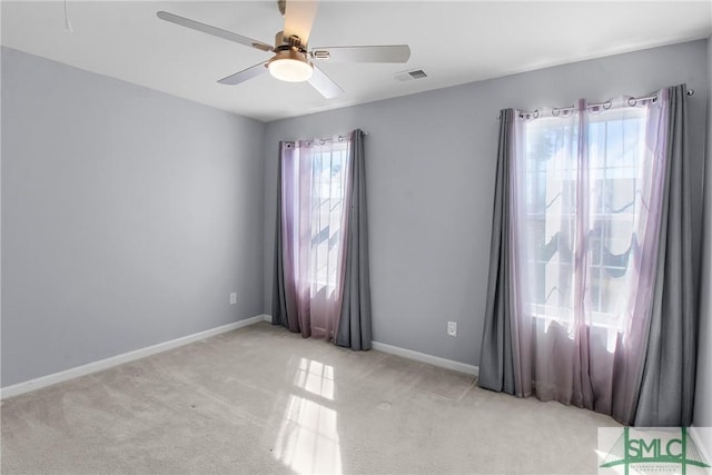 spare room featuring baseboards, light carpet, visible vents, and a ceiling fan