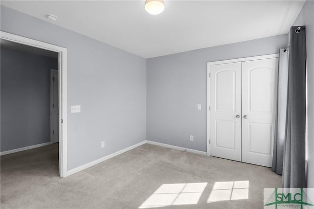 unfurnished bedroom featuring a closet, baseboards, and light colored carpet