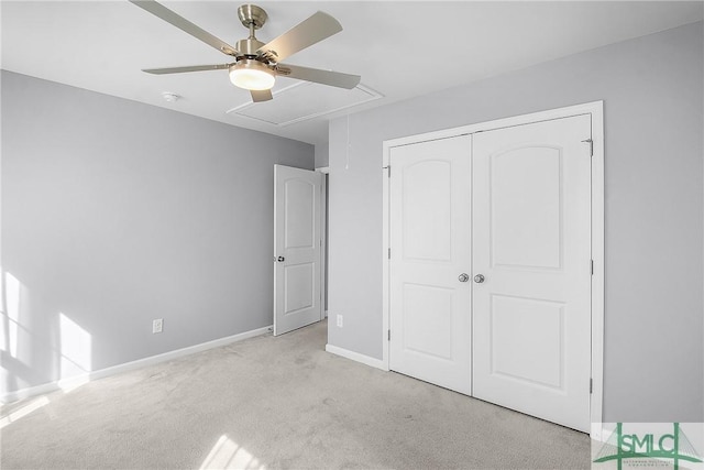 unfurnished bedroom featuring baseboards, attic access, light carpet, a closet, and a ceiling fan