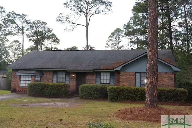 ranch-style home with brick siding, a front lawn, and a shingled roof