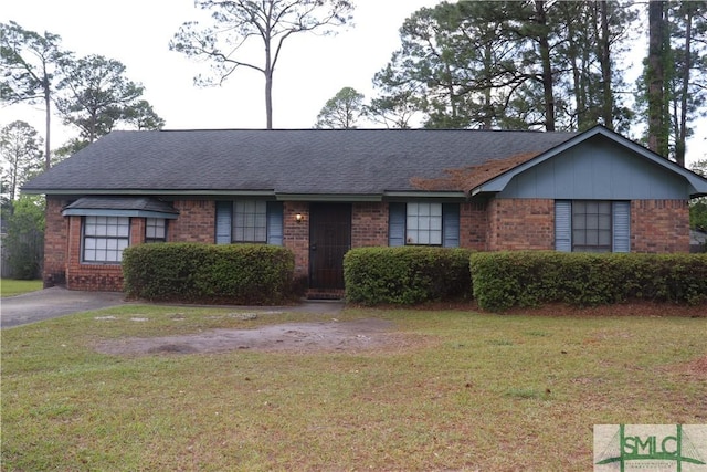 ranch-style home featuring brick siding, a front lawn, and roof with shingles