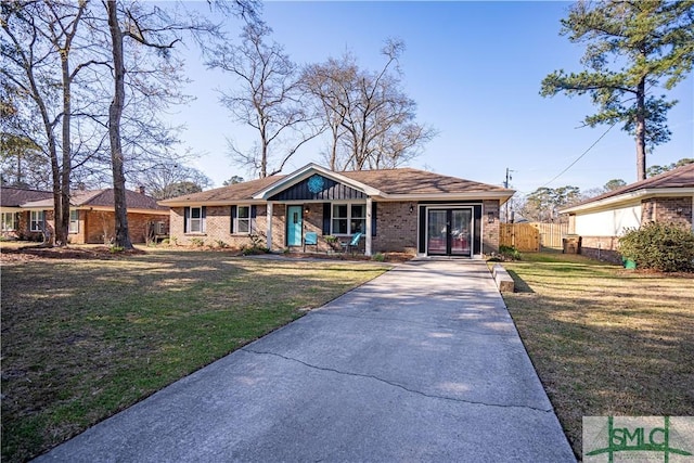 view of front of home featuring brick siding, driveway, a front lawn, and fence